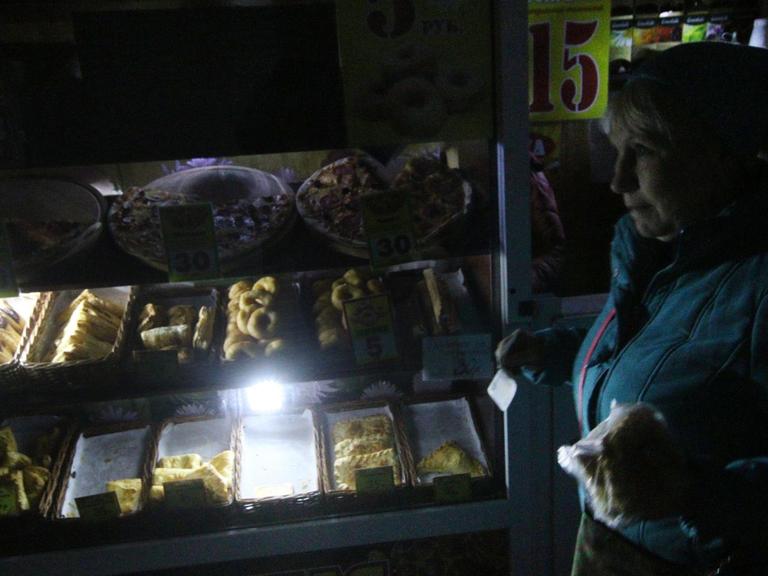 Eine Frau vor einem notdürftig beleuchteten Lebensmittelgeschäft