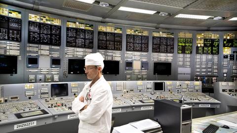Ein Ingenieur steht im Kontrollraum des Atomkraftwerks in Visaginas vor leuchtenden Kontrollpaneelen.
