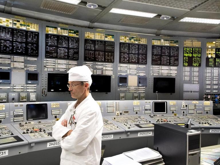 Ein Ingenieur steht im Kontrollraum des Atomkraftwerks in Visaginas vor leuchtenden Kontrollpaneelen.