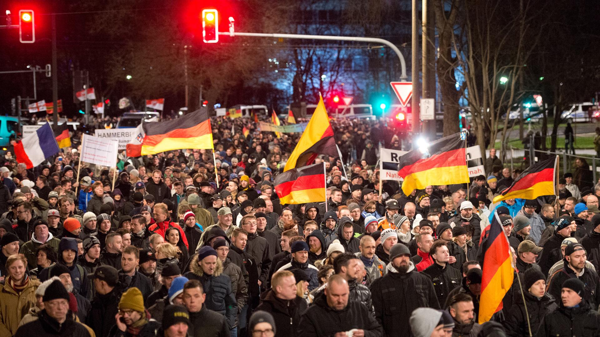 Eine Menschenmenge marschiert mit Deutschlandflaggen durch Dresden. Eine Menschenmenge marschiert mit Deutschlandflaggen durch Dresden.
