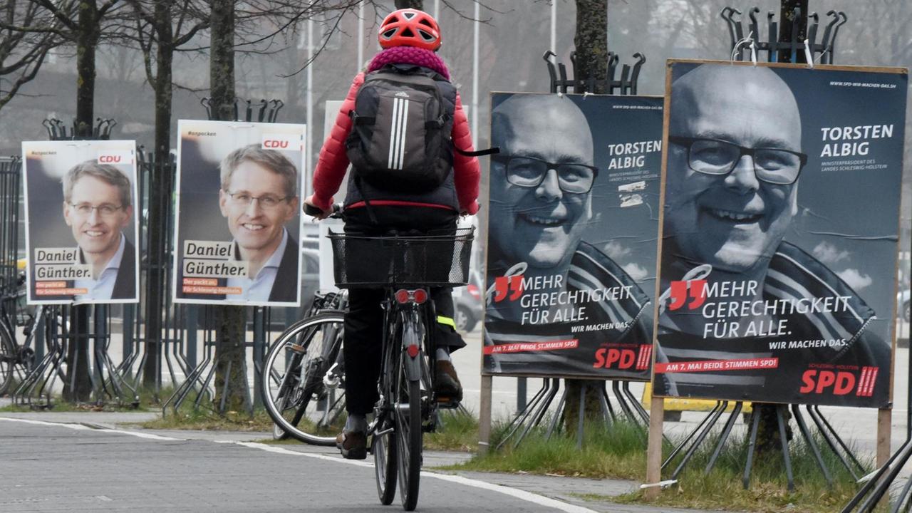 Ein Radfahrer fährt in Kiel an Wahlplakaten mit den Spitzenkandidaten der Landtagswahl, Daniel Günther (CDU) und Torsten Albig (SPD), vorbei Ein Radfahrer fährt in Kiel an Wahlplakaten mit den Spitzenkandidaten der Landtagswahl, Daniel Günther (CDU) und Torsten Albig (SPD), vorbei