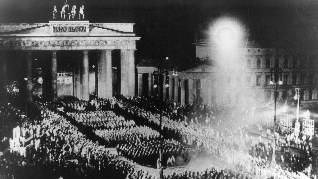 Für einen NS-Film nachgestellte Szene des Fackelzugs der SA durch das Brandenburger Tor, mit dem die Nationalsozialisten am 30.01.1933 die Machtübernahme feierten (Archivbild vom Sommer 1933). Für einen NS-Film nachgestellte Szene des Fackelzugs der SA durch das Brandenburger Tor, mit dem die Nationalsozialisten am 30.01.1933 die Machtübernahme feierten (Archivbild vom Sommer 1933).