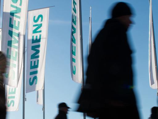 Siemens-Flaggen im Wind, davor laufen Menschen