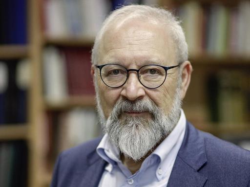 Politikwissenschaftler Herfried Münkler mit Brille und Bart vor einem Bücherregal.