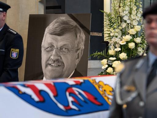 dpatopbilder - 13.06.2019, Hessen, Kassel: Das Konterfei von Walter Lübcke (CDU) ist hinter einem Bundeswehrsoldaten am Sarg bei einem Trauergottesdienst in der Martinskirche zu sehen. Lübcke wurde mit einem Kopfschuss auf der Terrasse seines Wohnhauses getötet. Foto: Swen Pförtner/dpa-POOL/dpa | Verwendung weltweit