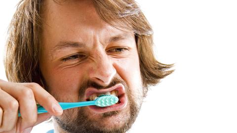 Ein Mann putzt seine Zähne.