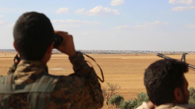 Kämpfer der Syrischen Demokratischen Streitkräfte mit Ferngläsern auf einem Aussichtspunkt beobachten die nordsyrische Stadt Manbidsch.