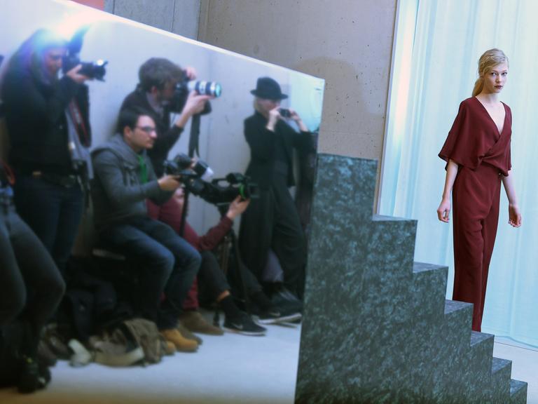 Ein Model präsentiert Mode vor mehreren Fotografen.