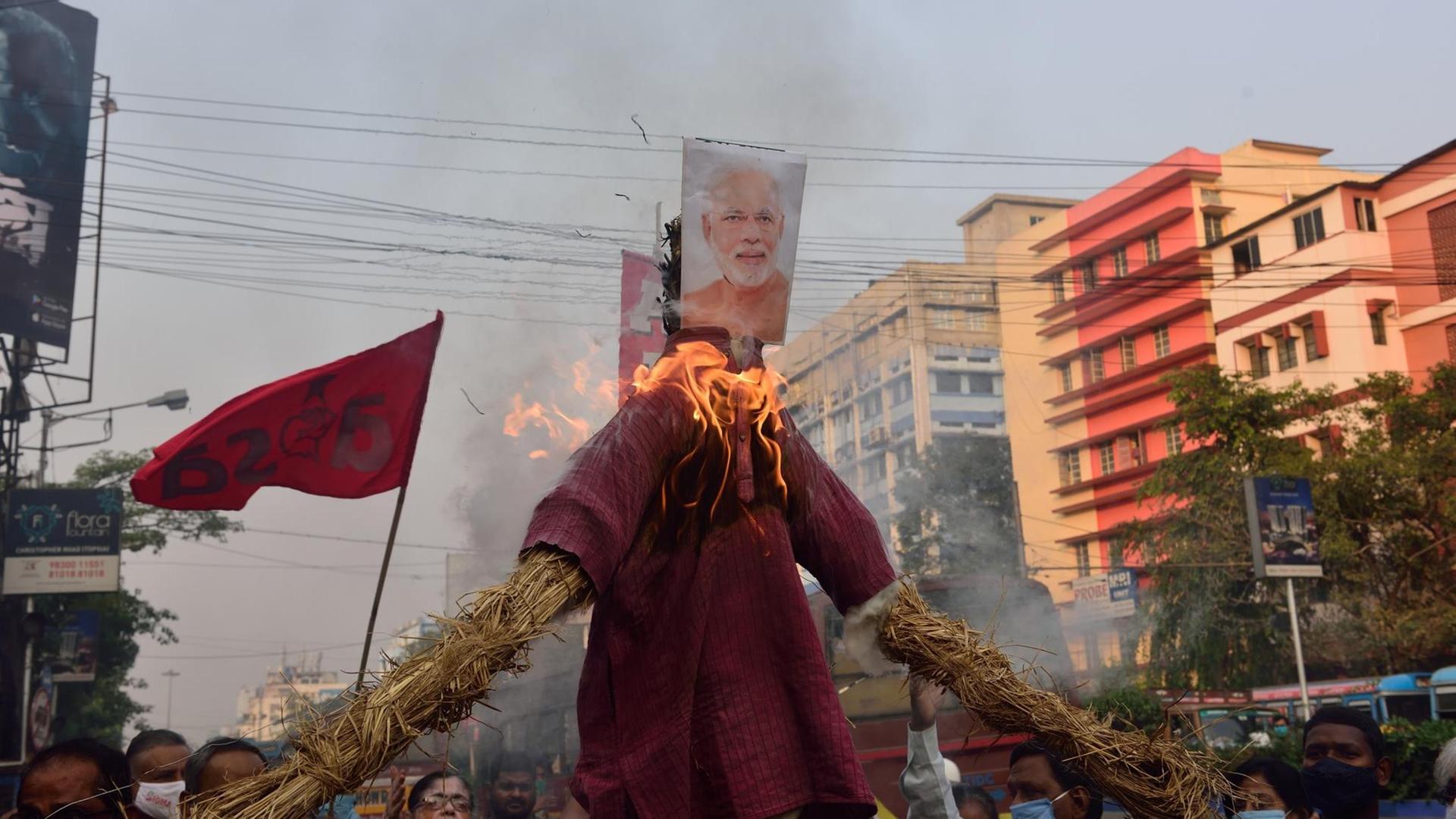 Demonstranten haben eine Abbildung des indischen Premierministers Modi an einer brennenden Figur aus Stroh befestigt, bei einem Protest gegen ein umstrittenes Paket neuer Landwirtschaftsgesetze. Demonstranten haben eine Abbildung des indischen Premierministers Modi an einer brennenden Figur aus Stroh befestigt, bei einem Protest gegen ein umstrittenes Paket neuer Landwirtschaftsgesetze.