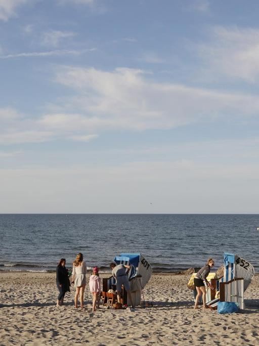 Blick auf den Strand mit Strandkörben und ein paar wenigen Menschen. Im Hintergrund die Ostsee.