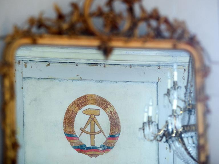 In einem Barockspiegel im restaurierten Schloss Kummerow ist am 05.05.2017 in Kummerow (Mecklenburg-Vorpommern) das Emblem der DDR zu sehen