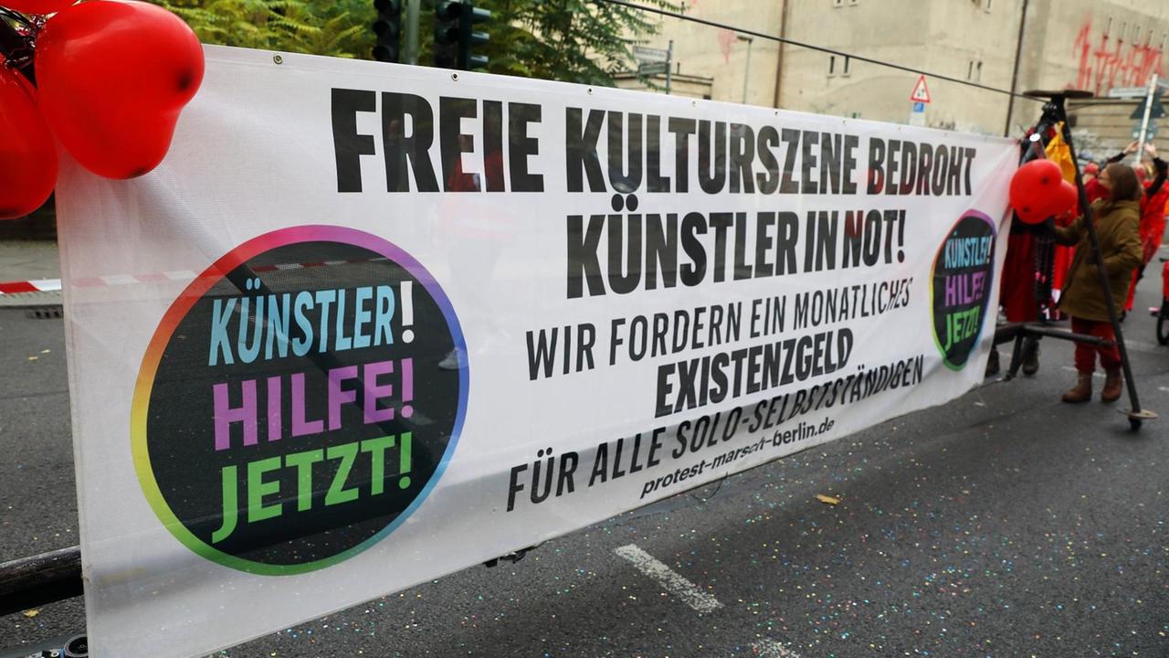 Die freie Kunstszene fordert bei einer Demo mit einem Transparent ein monatliches Existenzgeld während der Coronapandemie. Die freie Kunstszene fordert bei einer Demo mit einem Transparent ein monatliches Existenzgeld während der Coronapandemie.