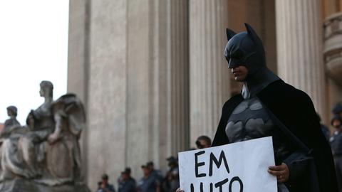 Ein Demonstrant im Batman-Kostüm in Rio de Janeiro während einer Protestaktion gegen die gestiegenen Preise im öffentlichen Nahverkehr in Brasilien. Auf dem Plakat steht: "Trauer um Santiago" – der Kameramann Santiago Andrade war kurz zuvor auf einer Demonstration ums Leben gekommen.