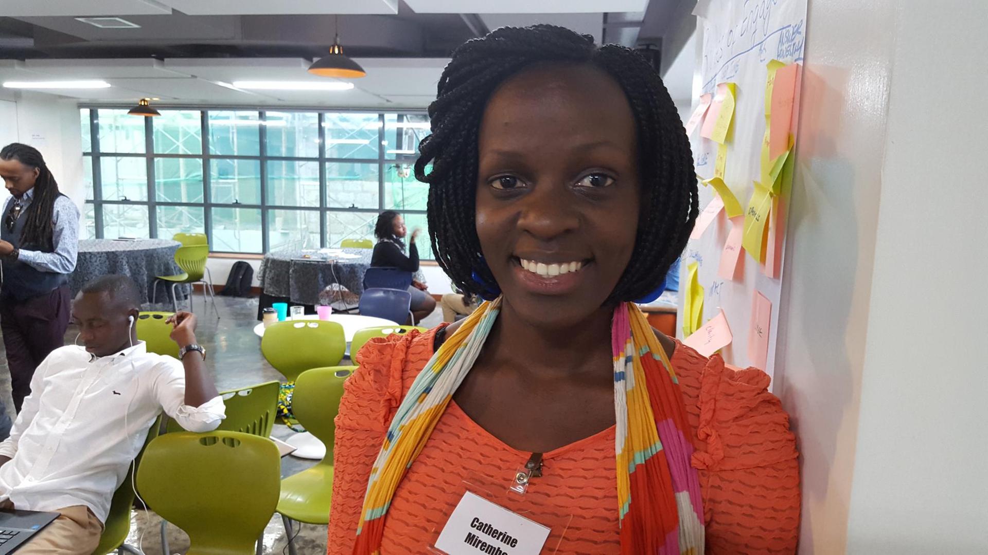 26-Jährige Firmengründerin Catherine Mirembe in Nairobis iHub. Sie lehnt an der Wand. Dahinter grüne Design-Stühle. 26-Jährige Firmengründerin Catherine Mirembe in Nairobis iHub. Sie lehnt an der Wand. Dahinter grüne Design-Stühle.
