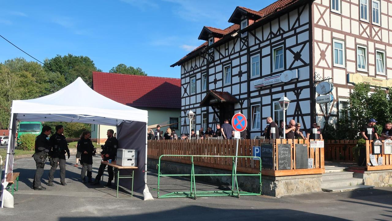 Vor dem Lokal steht eine Polizeiabsperrung, auf der Terrasse stehen einige weibliche und männliche Besucher, die die Absperrung passieren mussten Vor dem Lokal steht eine Polizeiabsperrung, auf der Terrasse stehen einige weibliche und männliche Besucher, die die Absperrung passieren mussten