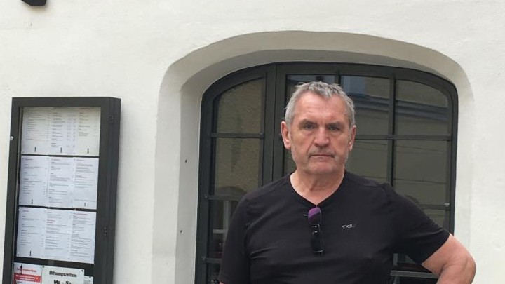 Walter Landshuter trägt eine schwarze Hose und ein schwarzes T-Shirt. Er steht vor seinem Karbarett "Scharfrichterhaus" in Passau.