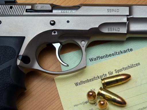 Eine Kaliber-9-mm-Pistole, Patronen und ein Magazin liegen auf einer Waffenbesitzkarte