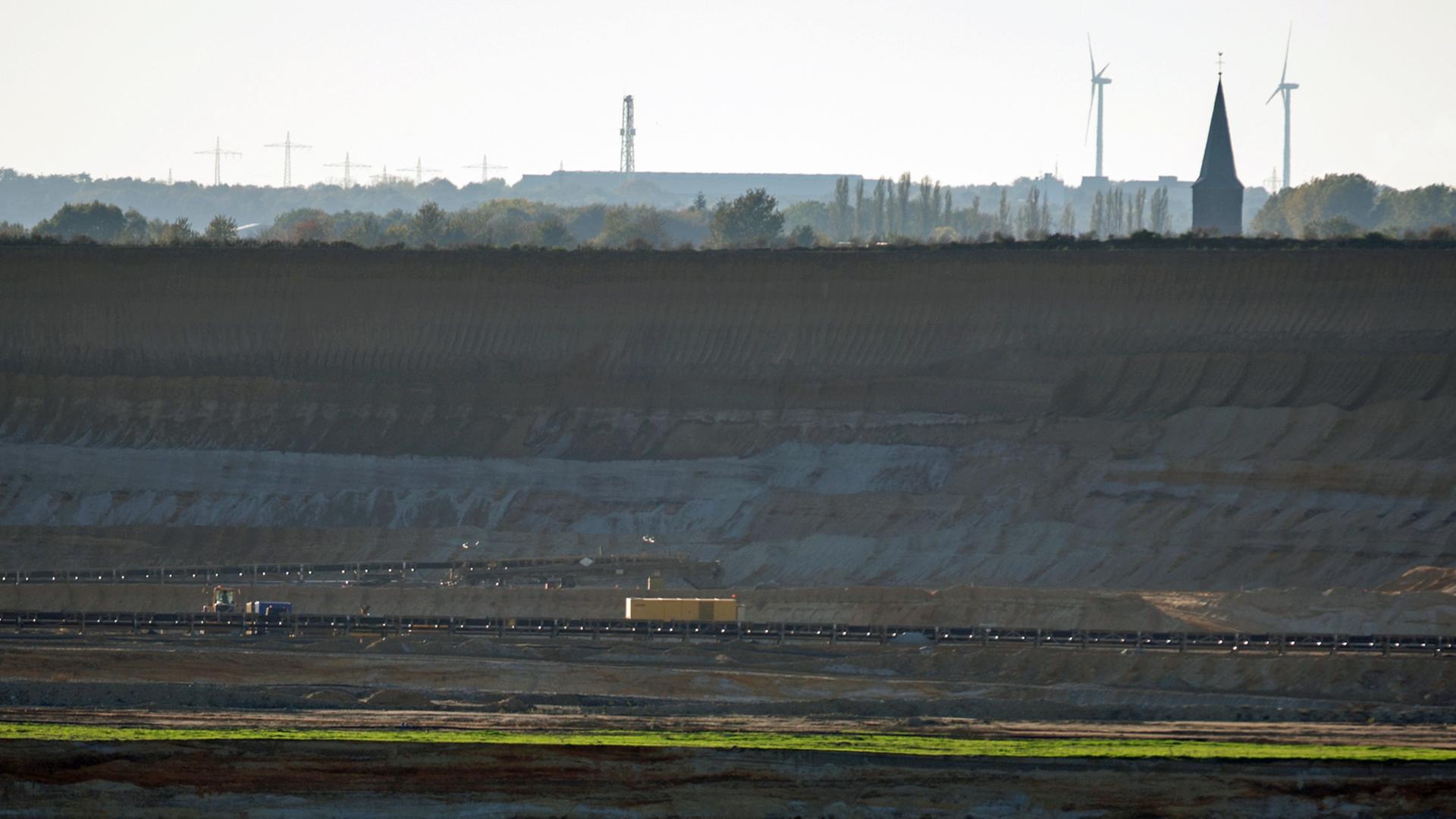 Tiefe Senke des Braunkohletagebaus "Garzweiler 2" bei Holz in Nordrhein-Westfalen: Der Kirchturm von Keyenberg und Windkraftanlagen sind im Hintergrund zu sehen; Aufnahme vom Oktober 2014 Tiefe Senke des Braunkohletagebaus "Garzweiler 2" bei Holz in Nordrhein-Westfalen: Der Kirchturm von Keyenberg und Windkraftanlagen sind im Hintergrund zu sehen; Aufnahme vom Oktober 2014