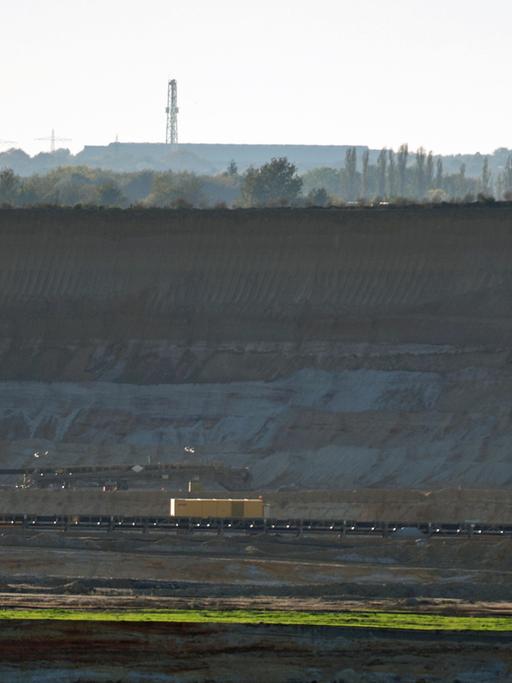 Tiefe Senke des Braunkohletagebaus "Garzweiler 2" bei Holz in Nordrhein-Westfalen: Der Kirchturm von Keyenberg und Windkraftanlagen sind im Hintergrund zu sehen; Aufnahme vom Oktober 2014