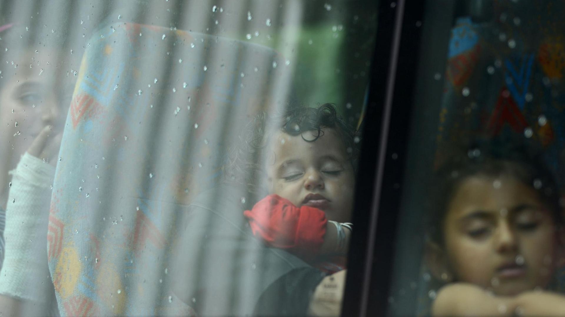 Drei Flüchtlingskinder sitzend schlafend hintereinander in einem Bus an einer Asylbewerber-Registrierungsstelle der Bundespolizei in Passau.