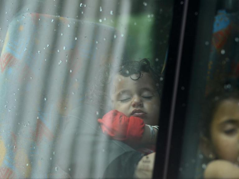 Drei Flüchtlingskinder sitzend schlafend hintereinander in einem Bus an einer Asylbewerber-Registrierungsstelle der Bundespolizei in Passau.
