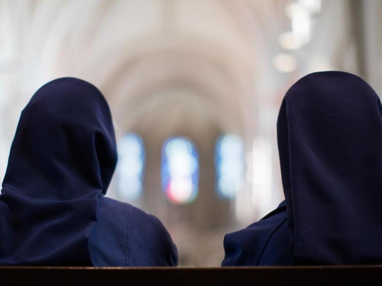 Zwei Ordensschwestern sitzen im Dom.