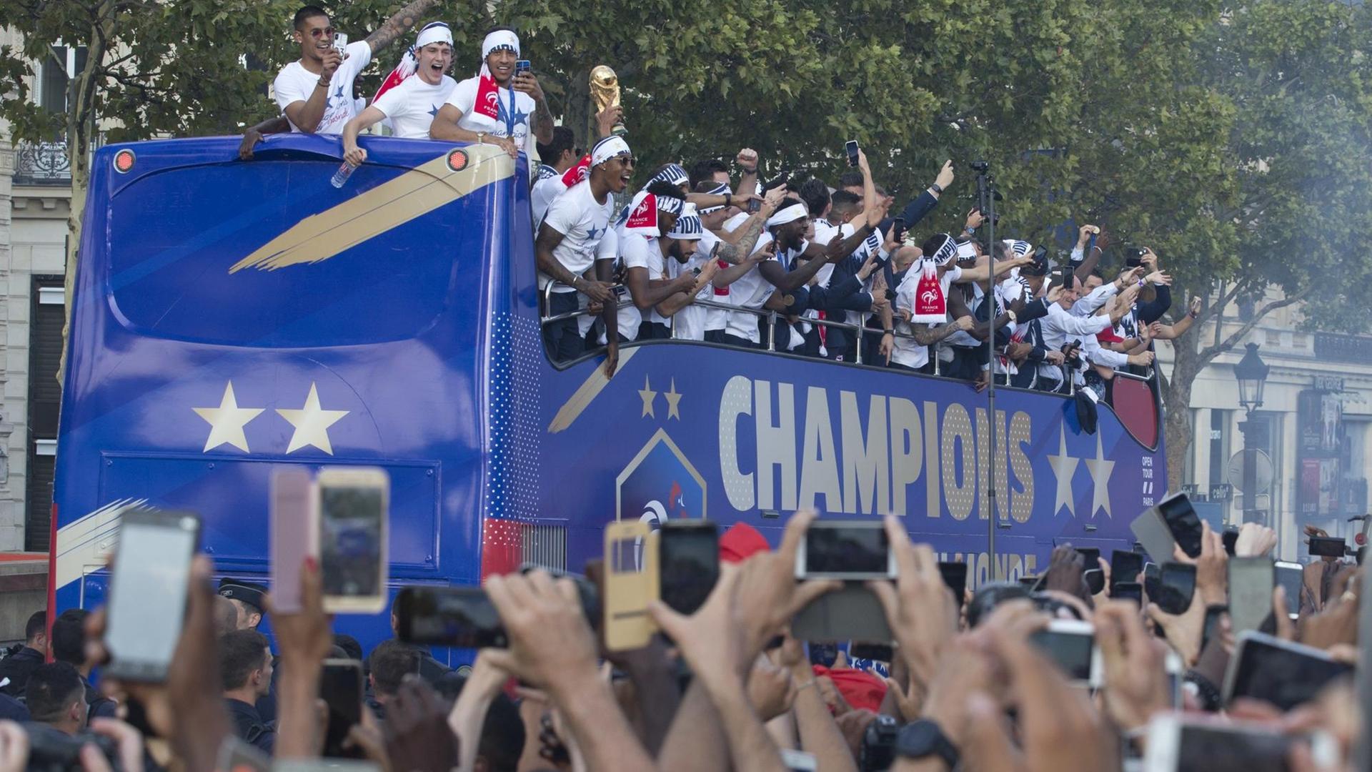 Die Spieler stehen auf einem offenen Doppeldecker-Bus mit der Aufschrift "Champions". Sie tragen weiße T-Shirts und winken den jubelnden Zuschauern zu. Die Spieler stehen auf einem offenen Doppeldecker-Bus mit der Aufschrift "Champions". Sie tragen weiße T-Shirts und winken den jubelnden Zuschauern zu.
