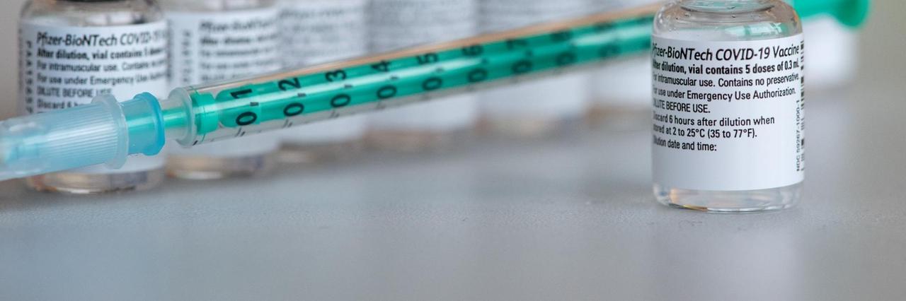 Leere Ampullen des Impfstoffs von Biontech/Pfizer gegen das Corona-Virus SARS-CoV-2 stehen in einem Impfzentrum nach der Vorbereitung der Spritzen auf einem Tisch.