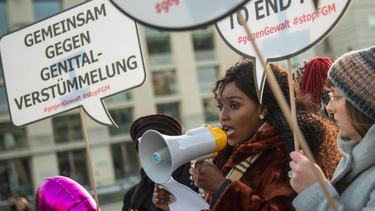 Frauen mit Megafon und Plakaten "Gemeinsam gegen Genitalverstümmelung". Frauen mit Megafon und Plakaten "Gemeinsam gegen Genitalverstümmelung".