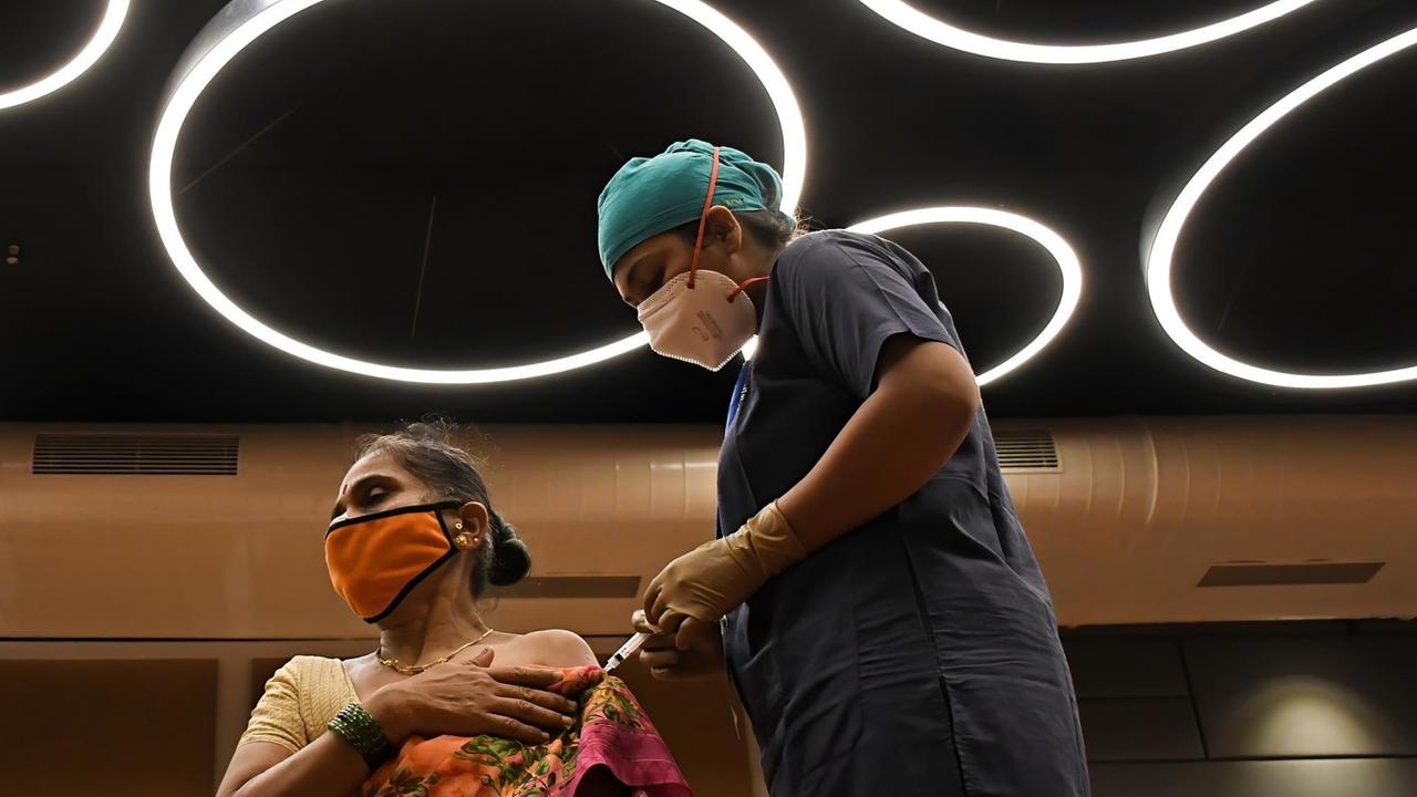 Eine Gesundheitsmitarbeiterin impft eine Frau in Mumbai, Indien. Eine Gesundheitsmitarbeiterin impft eine Frau in Mumbai, Indien.