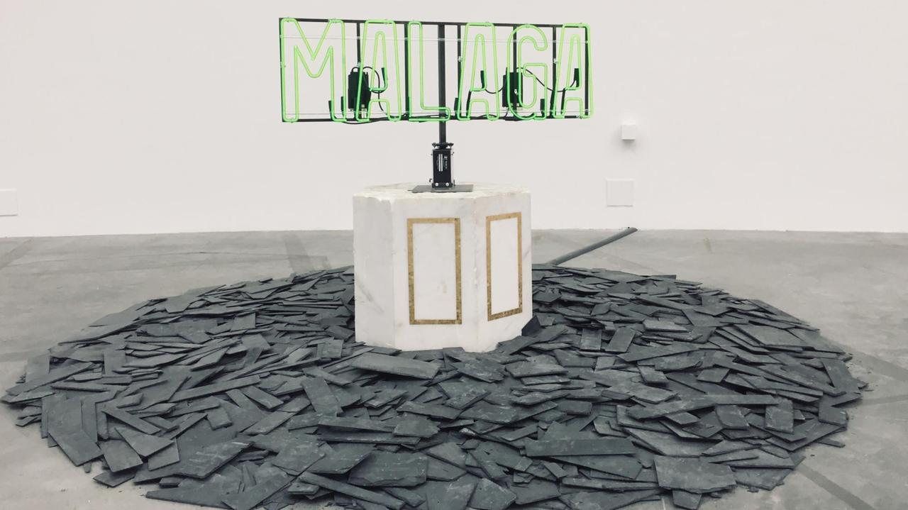 Ein Werk aus der Ausstellung "Amalgam" des US-Amerikaners Theaster Gates im Palais de Tokyo Paris. Zerschlagene Schieferplatten auf einem Haufen, in der Mitte ein Marmorblock mit einem Metallgestänge, auf dem eine neongrüne Leuchtschrift steht: zu lesen ist "MALAGA". Ein Werk aus der Ausstellung "Amalgam" des US-Amerikaners Theaster Gates im Palais de Tokyo Paris. Zerschlagene Schieferplatten auf einem Haufen, in der Mitte ein Marmorblock mit einem Metallgestänge, auf dem eine neongrüne Leuchtschrift steht: zu lesen ist "MALAGA".