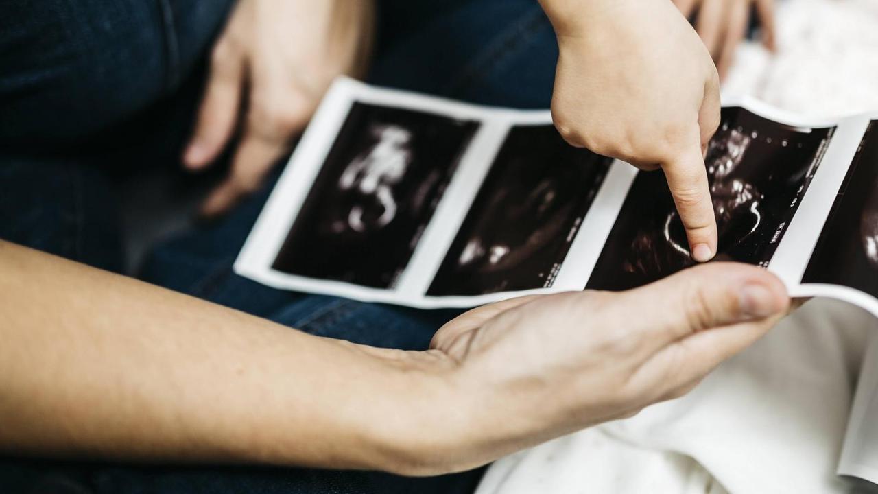 Eine Mutter und ein Junge betrachten ein Ultraschall-Bild Eine Mutter und ein Junge betrachten ein Ultraschall-Bild