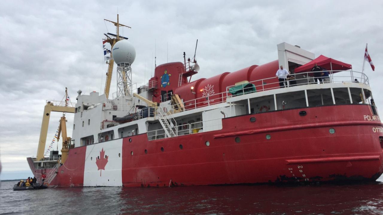 Im Meer liegt das große, rote C3-Expeditionsschiff mit kanadischer Flagge.