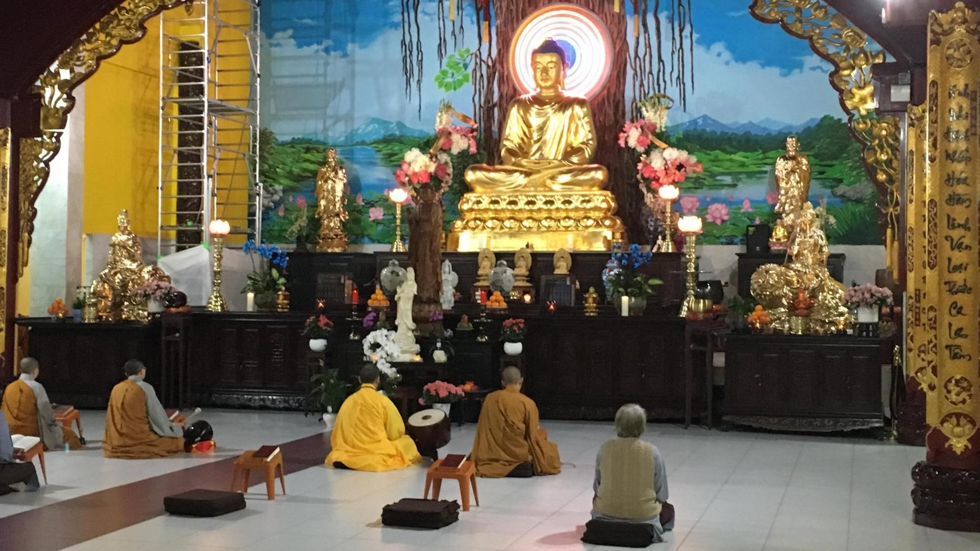 Lehre der buddhistischen Schule des Mahayana: Gebetsraum mit dem goldenen Buddha im Lotussitz auf einem farbenprächtig geschmückten Altar Lehre der buddhistischen Schule des Mahayana: Gebetsraum mit dem goldenen Buddha im Lotussitz auf einem farbenprächtig geschmückten Altar
