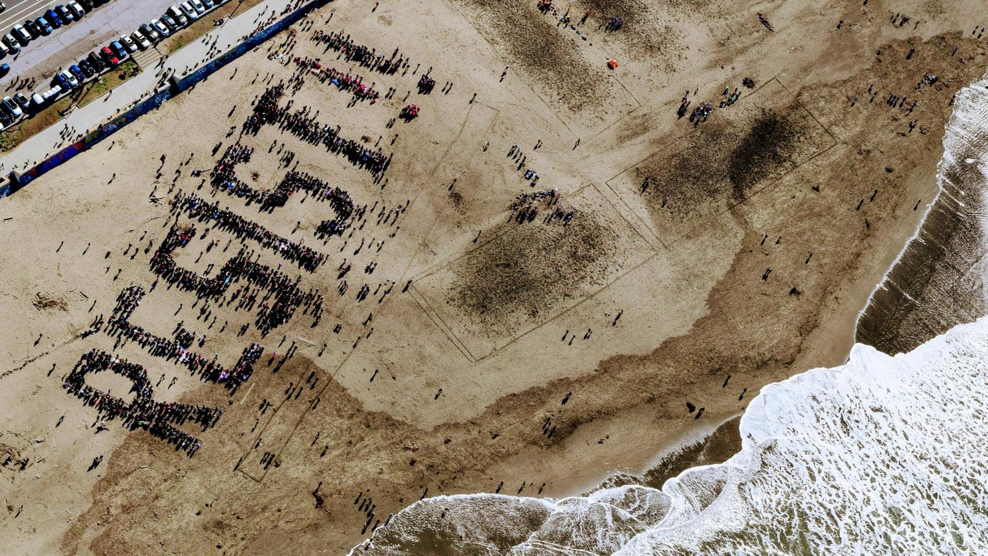 Menschen am Ocean Beach in San Francisco formen das Wort "Resist" am Strand. Menschen am Ocean Beach in San Francisco formen das Wort "Resist" am Strand.