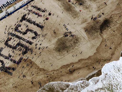 Menschen am Ocean Beach in San Francisco formen das Wort "Resist" am Strand.