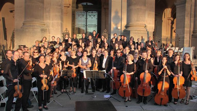 Musikerinnen und Musiker des Lietzeorchesters stehen mit ihren Instrumenten vor einem Portal Musikerinnen und Musiker des Lietzeorchesters stehen mit ihren Instrumenten vor einem Portal