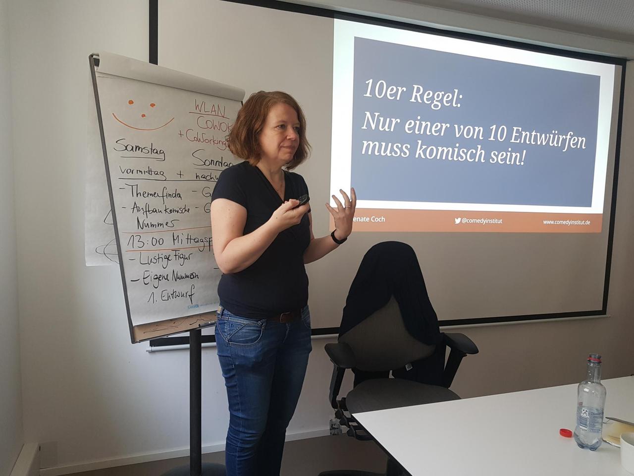 Renate Coch, Leiterin des Seminars „Handwerk Comedy“, steht vor den Teilnehmern. Hinter hier wird über einen Beamer ihre Präsentation an die Wand projiziert. Darauf zu lesen steht: "10er Regel: Nur einer von 10 Entwürfen muss komisch sein." Renate Coch, Leiterin des Seminars „Handwerk Comedy“, steht vor den Teilnehmern. Hinter hier wird über einen Beamer ihre Präsentation an die Wand projiziert. Darauf zu lesen steht: "10er Regel: Nur einer von 10 Entwürfen muss komisch sein."