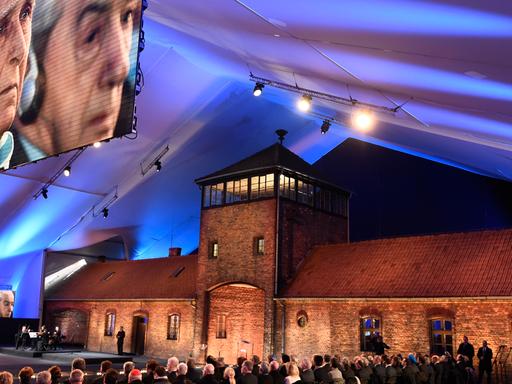 Bei der Gedenkveranstaltung vor dem Eingang des Konzentrationslagers Auschwitz ist ein Überlebender des Holocaust auf einer großen Leinwand zu sehen.