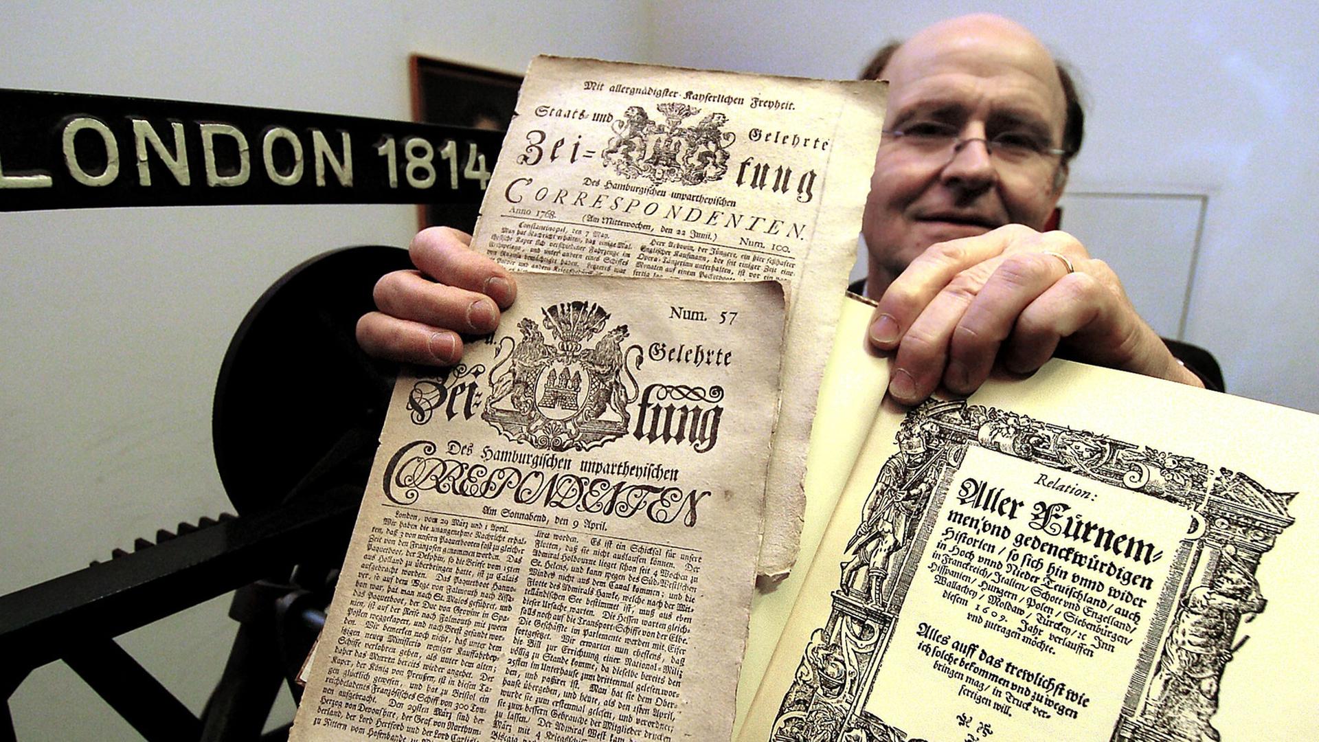 Der Kurator der Jubiläumssausstellung "400 Jahre Zeitung", Martin Welke, zeigt im Mainzer Gutenberg-Museum das Faksimile der ersten Zeitung der Welt, der Straßburger "Relation aller Fürnemmen und gedenckwürdigen Historien" und zwei Exemplare des "Hamburgischen Unpartheyischen Correspondent" aus dem 18. Jahrhundert. Werner Baum Der Kurator der Jubiläumssausstellung "400 Jahre Zeitung", Martin Welke, zeigt im Mainzer Gutenberg-Museum das Faksimile der ersten Zeitung der Welt, der Straßburger "Relation aller Fürnemmen und gedenckwürdigen Historien" und zwei Exemplare des "Hamburgischen Unpartheyischen Correspondent" aus dem 18. Jahrhundert. Werner Baum