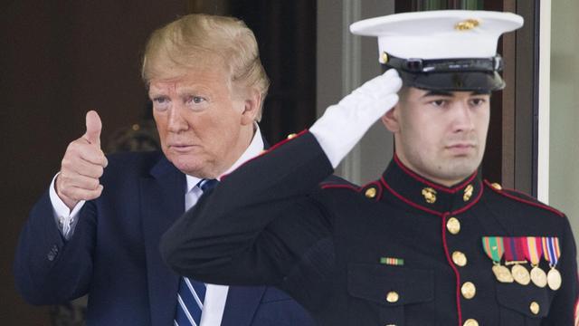 US-Präsident Donald Trump gestikuliert. Vor ihm salutiert ein Mann in Militäruniform.