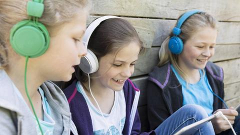 Mädchen hören gemeinsam Musik und schauen auf Tablets
