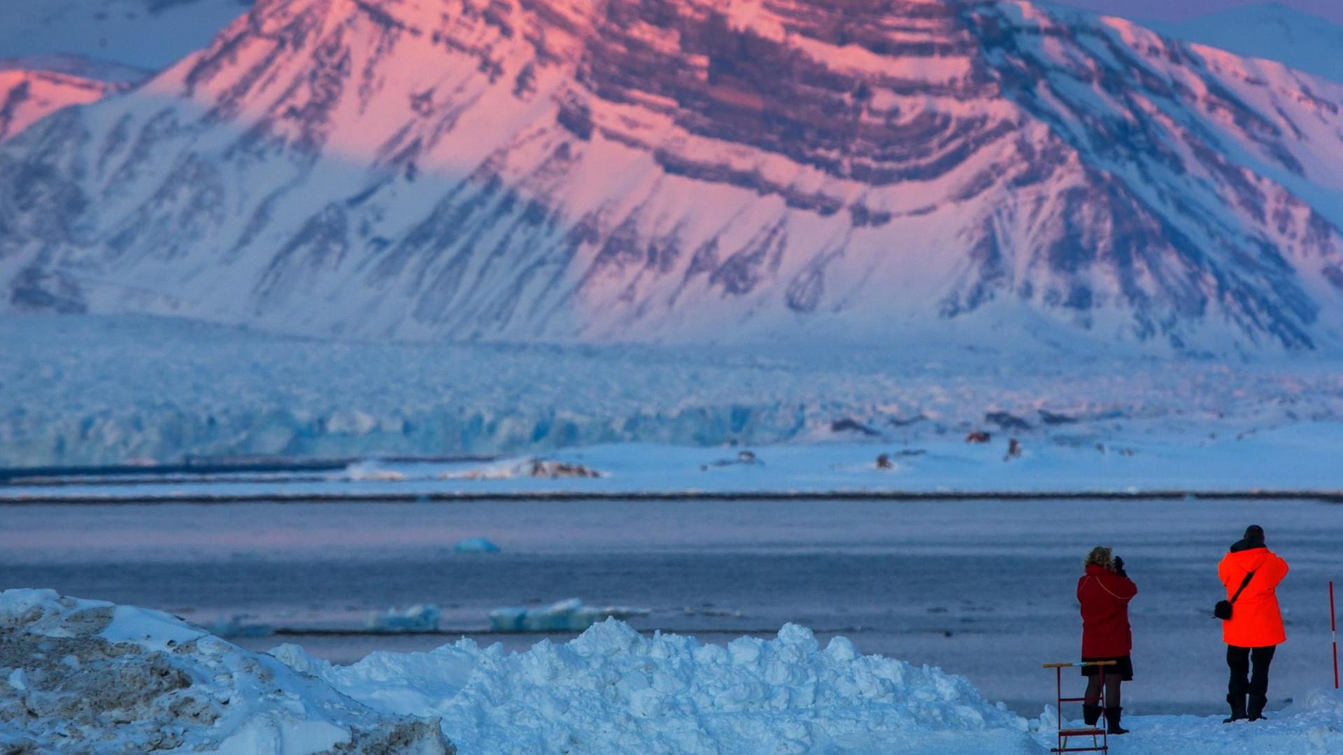 Besucher fotografieren am 09.04.2015 die von der untergehenden Sonne angeleuchteten Spitzen der "Tre Kroner" am Kongsfjord-Gletscher in Ny-Ålesund auf Spitzbergen (Norwegen). Besucher fotografieren am 09.04.2015 die von der untergehenden Sonne angeleuchteten Spitzen der "Tre Kroner" am Kongsfjord-Gletscher in Ny-Ålesund auf Spitzbergen (Norwegen).
