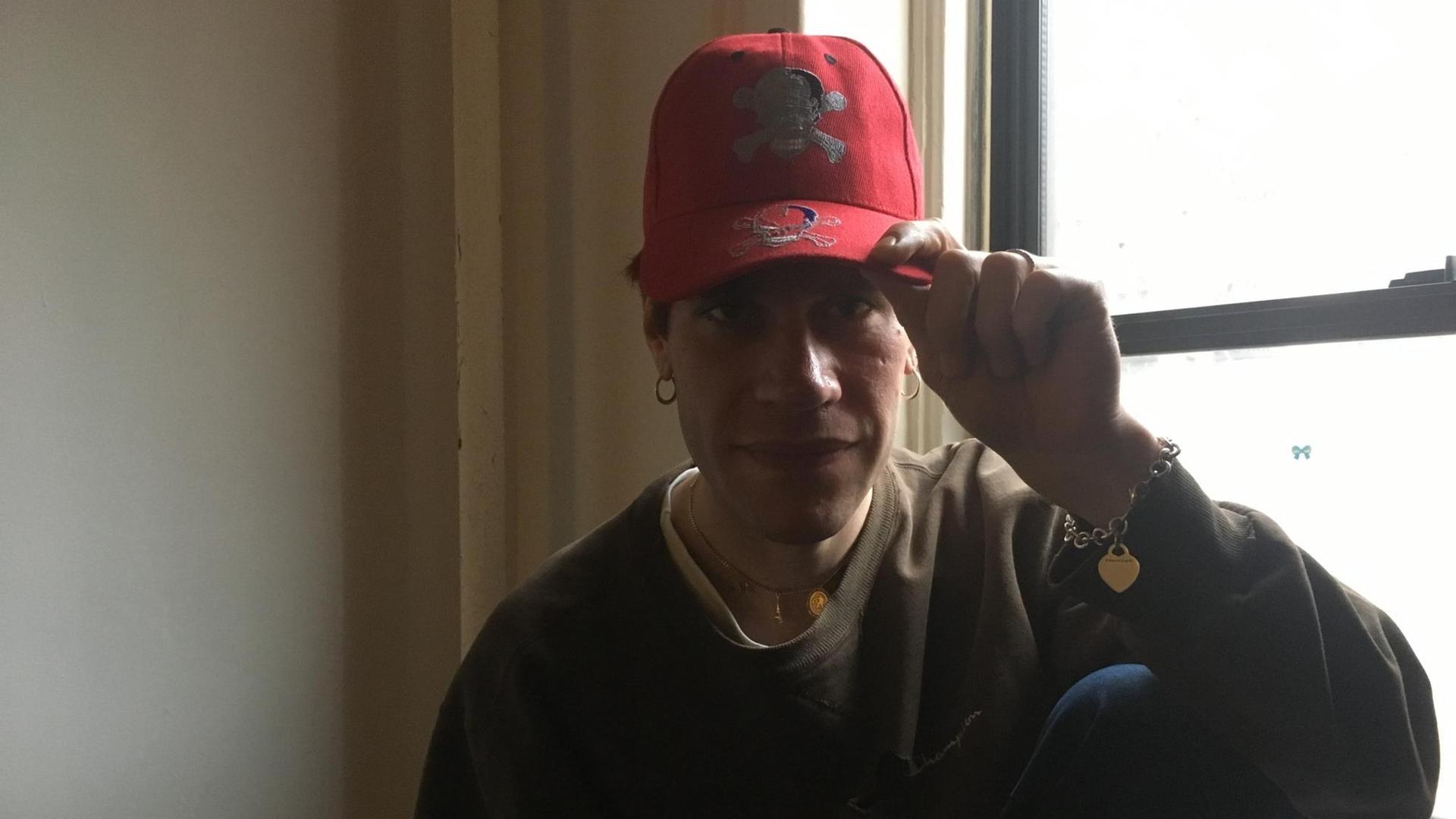 Aaron Maine blickt ernst in die Kamera. Er trägt eine rote Baseballcap Aaron Maine blickt ernst in die Kamera. Er trägt eine rote Baseballcap