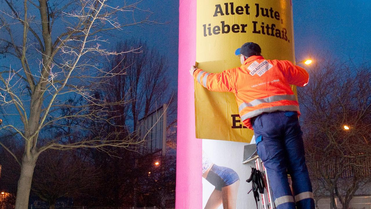 Eine Litfaß-Säule in Berlin wird neu beklebt Eine Litfaß-Säule in Berlin wird neu beklebt