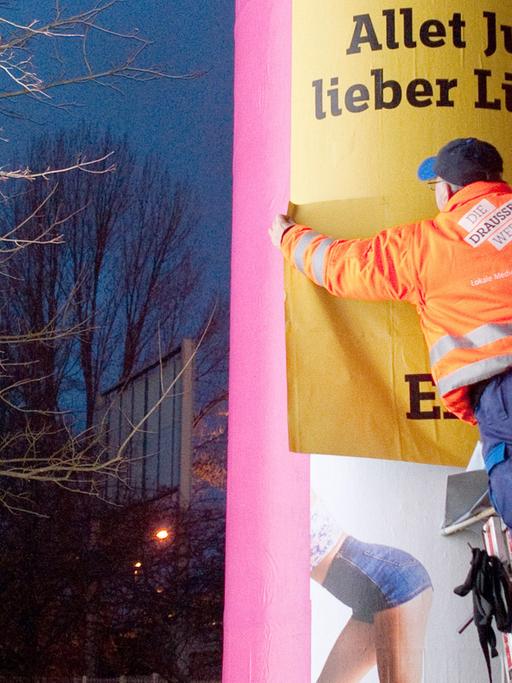 Eine Litfaß-Säule in Berlin wird neu beklebt