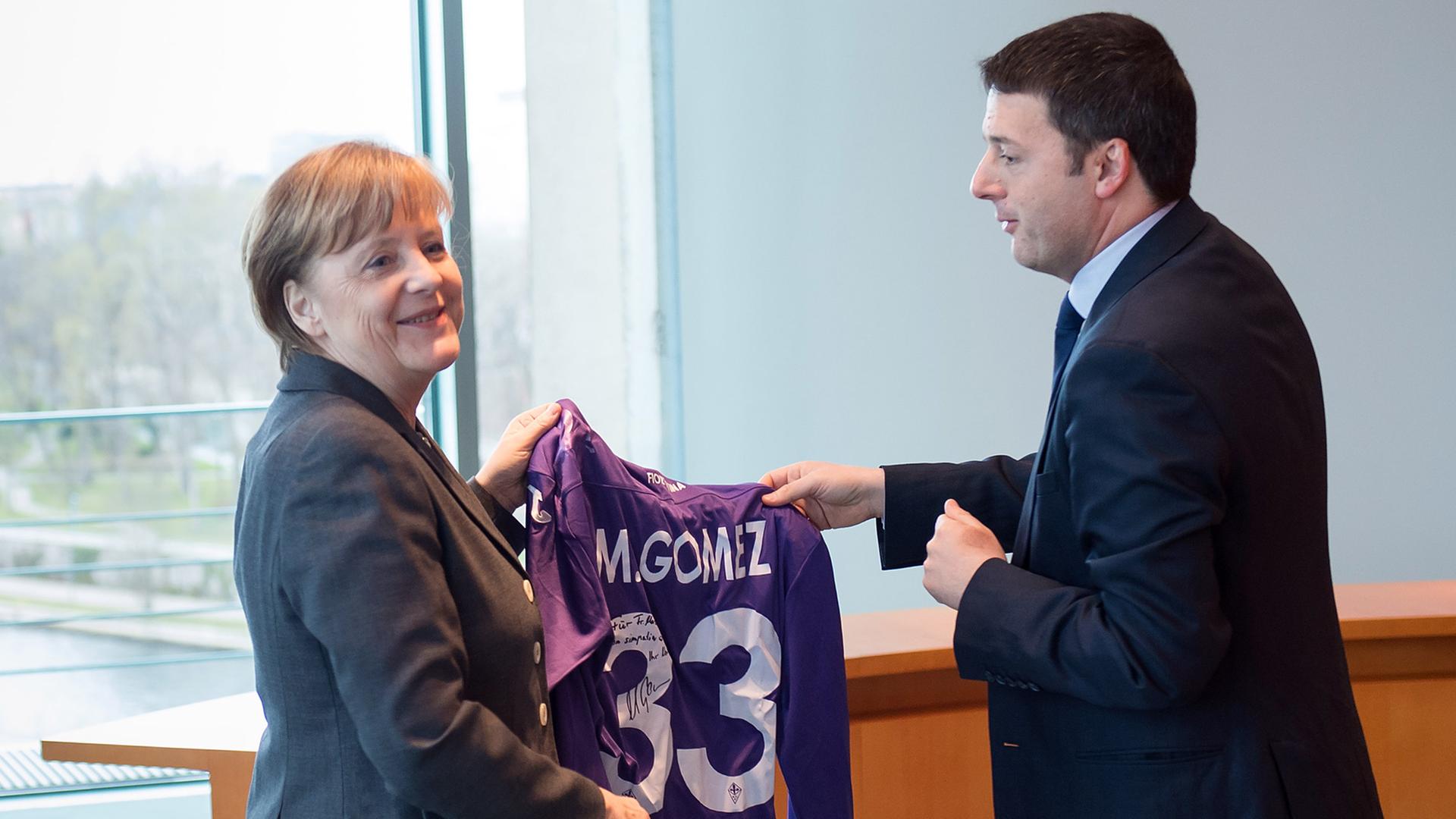 Bundeskanzlerin Angela Merkel erhält vom italienischen Ministerpräsidenten Matteo Renzi anlässlich der deutsch-italienischen Regierungskonsultationen am 17.03.2014 in Berlin ein signiertes Trikot des deutschen Fußball-Nationalspielers Mario Gomez, der für den AC Florenz spielt Bundeskanzlerin Angela Merkel erhält vom italienischen Ministerpräsidenten Matteo Renzi anlässlich der deutsch-italienischen Regierungskonsultationen am 17.03.2014 in Berlin ein signiertes Trikot des deutschen Fußball-Nationalspielers Mario Gomez, der für den AC Florenz spielt