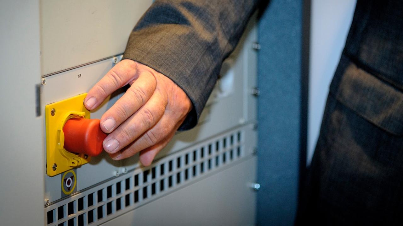 Eine Hand drückt auf einen roten Knopf