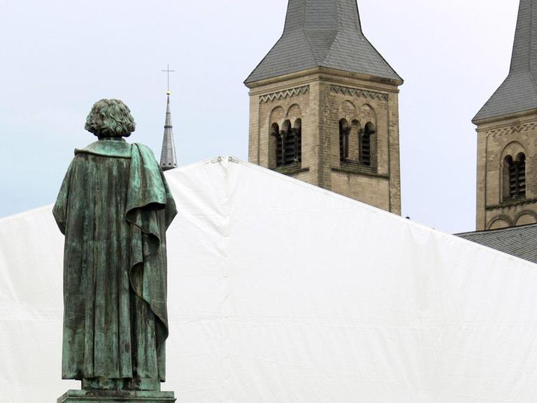 Die Bonner Statue Beethovens in Rückenansicht, die scheinbar auf die Türme des Bonner Münsters schaut.