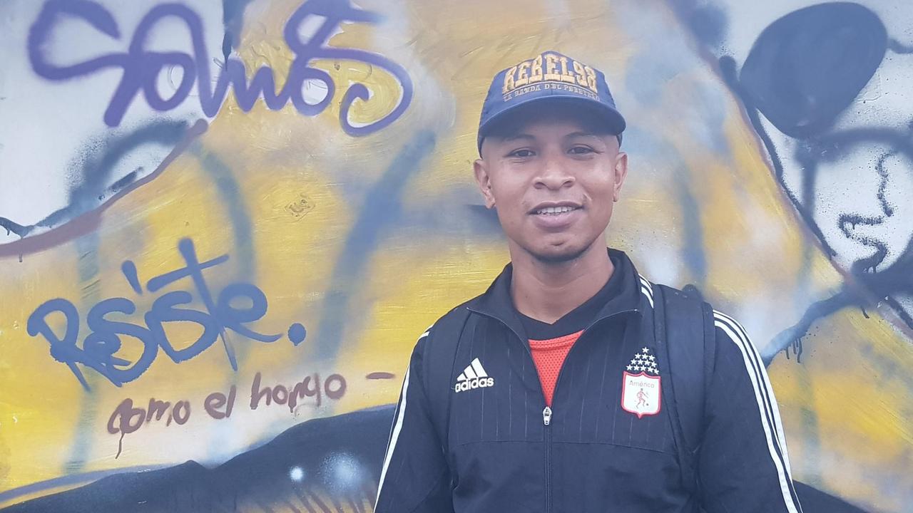 Ein junger Mann mit Basecap steht vor einer besprühten Wand. Ein junger Mann mit Basecap steht vor einer besprühten Wand.